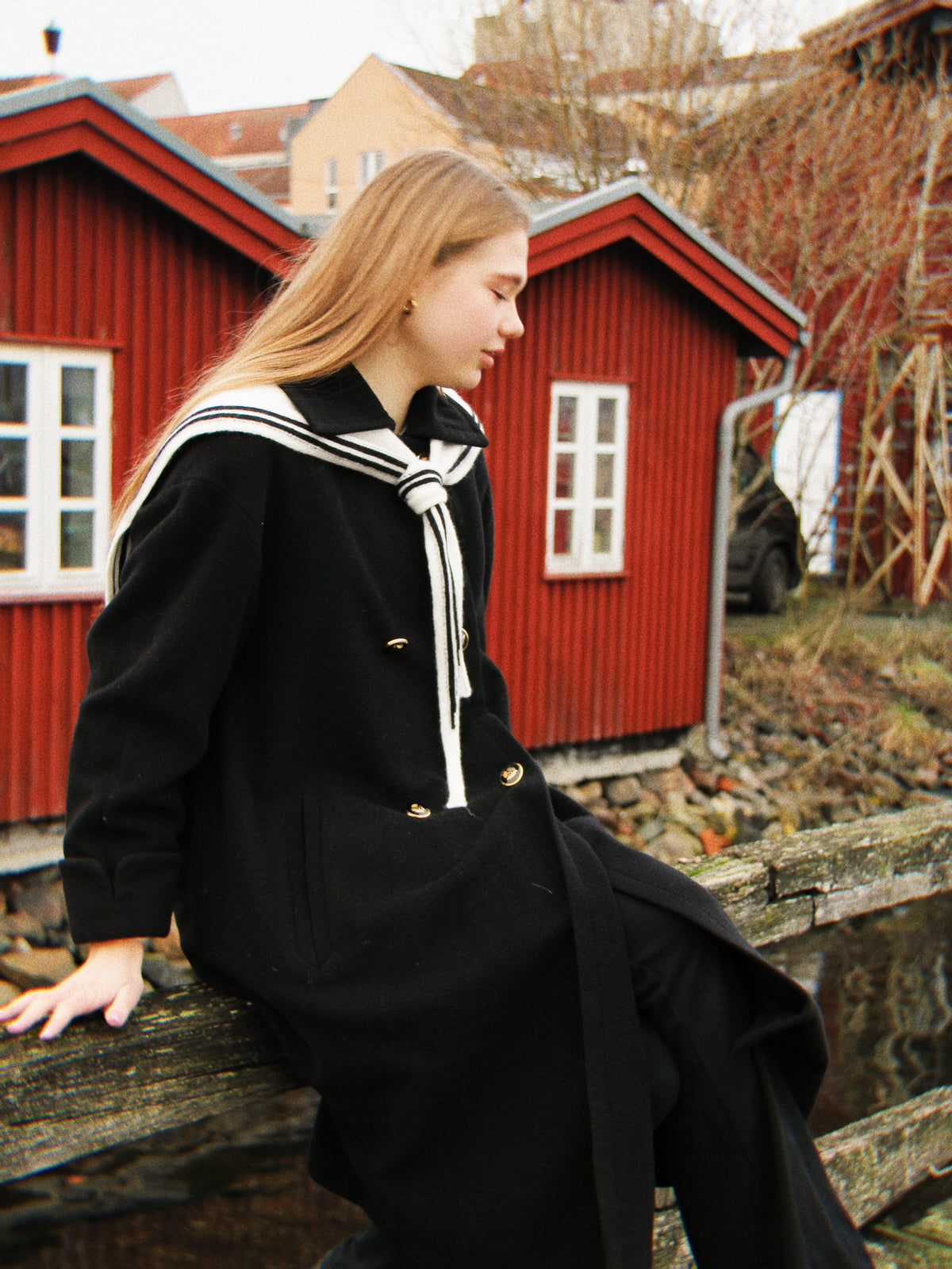 Blondes Mädchen vor roten Bootshäusern