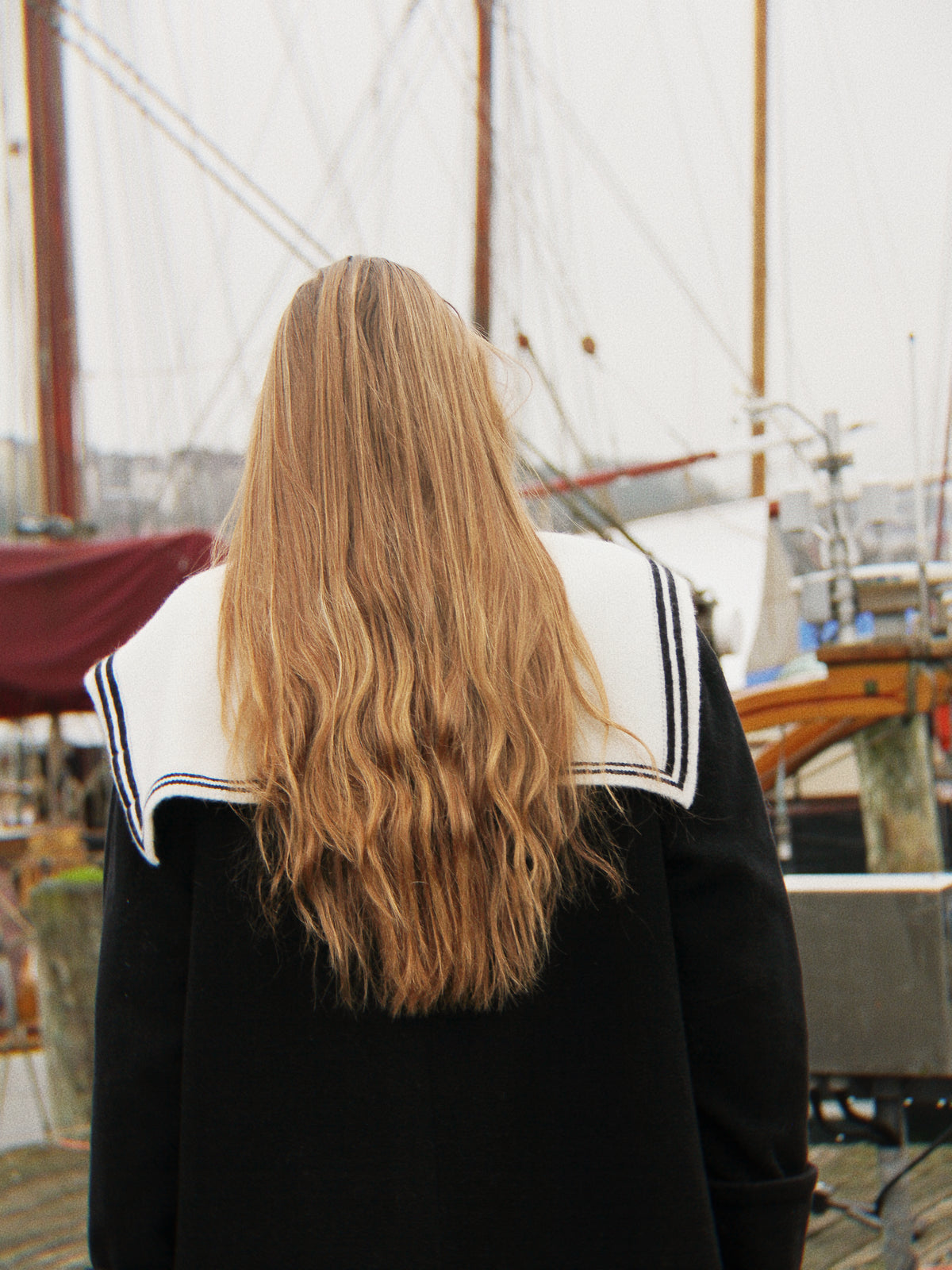 Blondes Mädchen vor Segelbooten mit Aglaea Studio Matrosenkragen aus Merinowolle